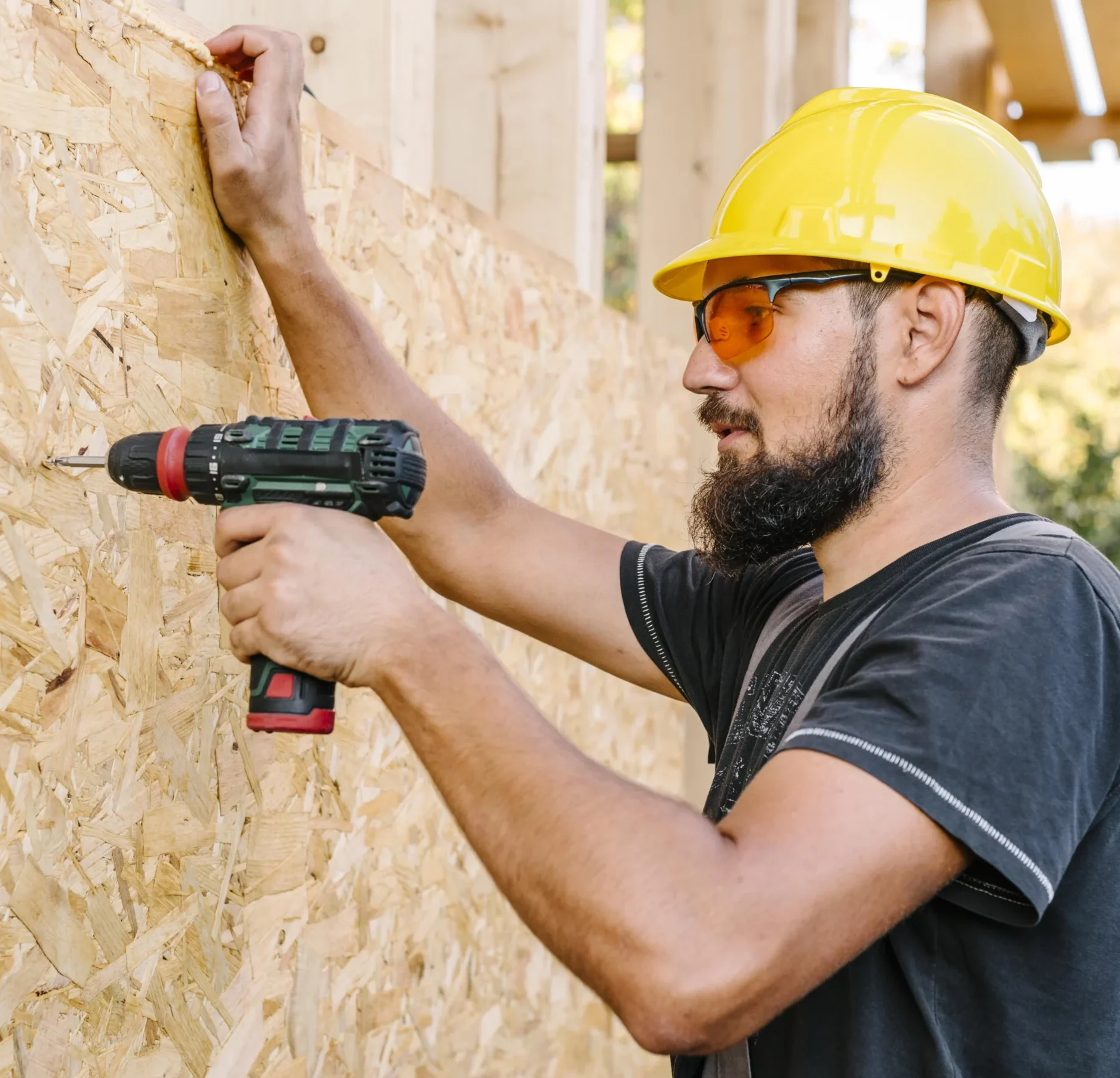 Ouvrier en train de visser un panneau isolant en bois sur une façade dans le cadre de travaux pour besi expert en isolation thermique par l’extérieur entreprise isolation rge